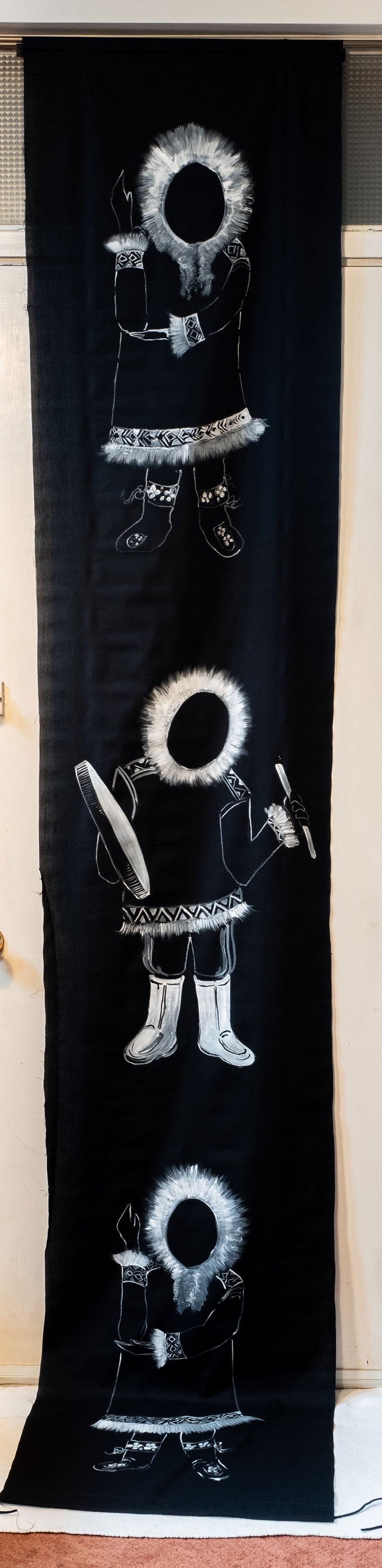 Inuit dancers in black and white on a tall banner.