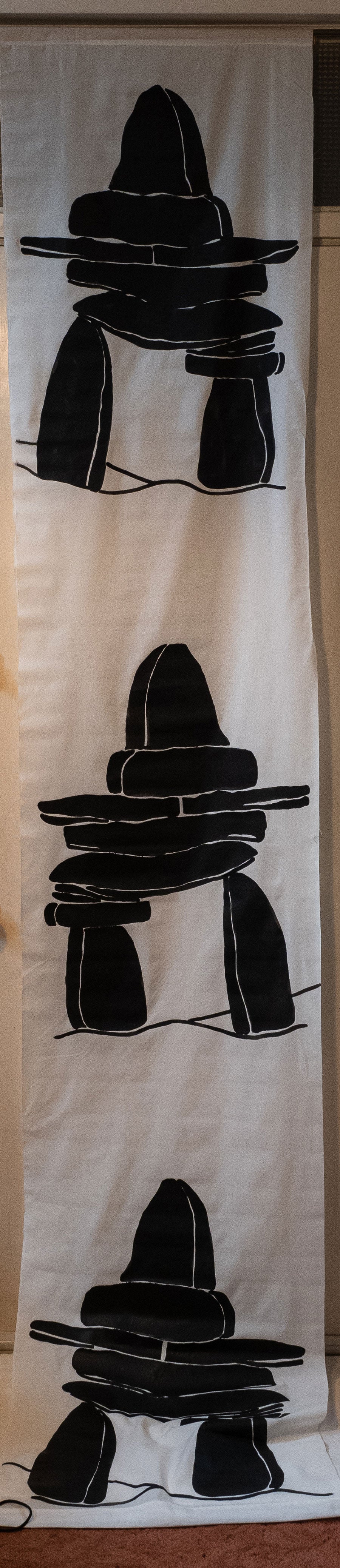 Inukshuks in black and white on a tall banner.